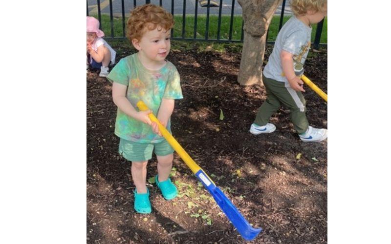 Boy raking dirt at preschool